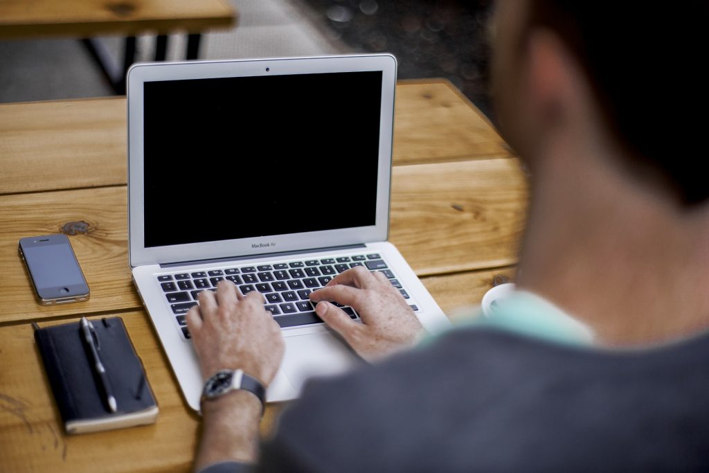 man sitting at a desk, using his laptop