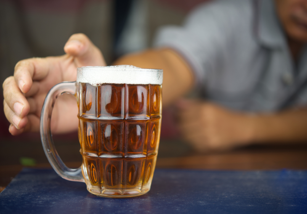 Man reaching for a mug of beer. With moderation and the right selection, drinking beer and dieting can be done at the same time.