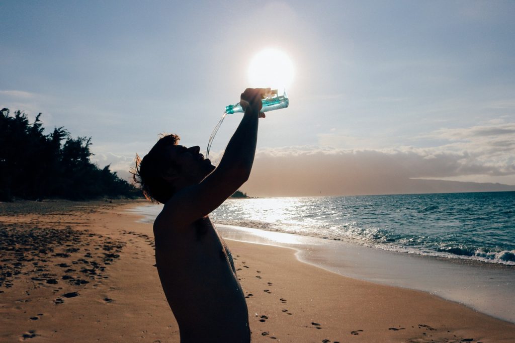 man drinking water on the beach