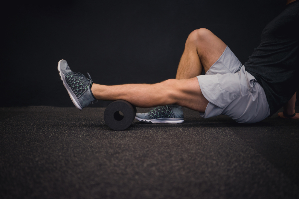 Man using foam roller on his calf muscle. Great for winter workouts.