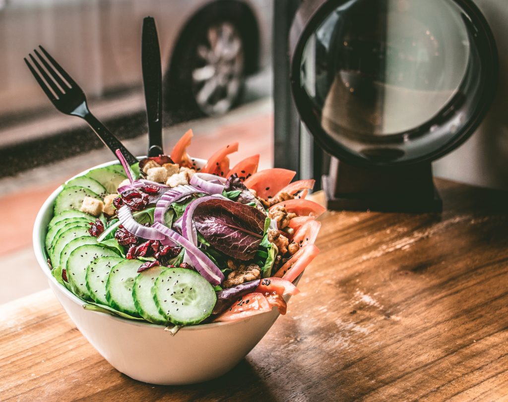 A bowl of vegetable salad. Doing holiday workout and eating healthy food will help you stay in shape during the holidays.