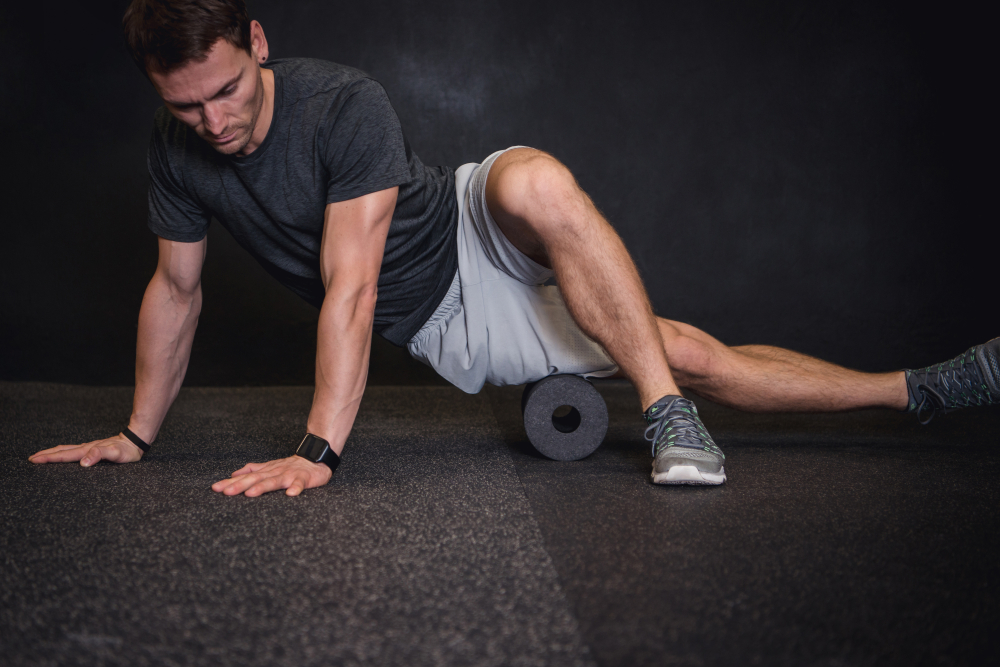 Man using muscle roller on his thigh as a tool for preventive maintenance.