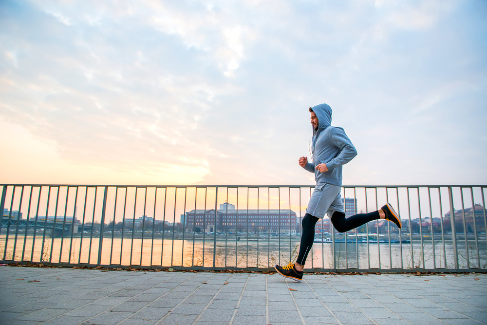 man running in the sunset next to a fence on the riverside