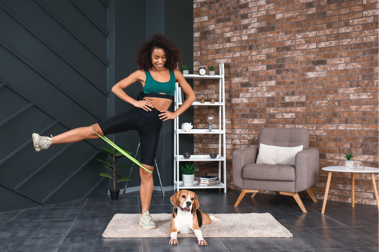 Sporty woman with cute dog training at home.