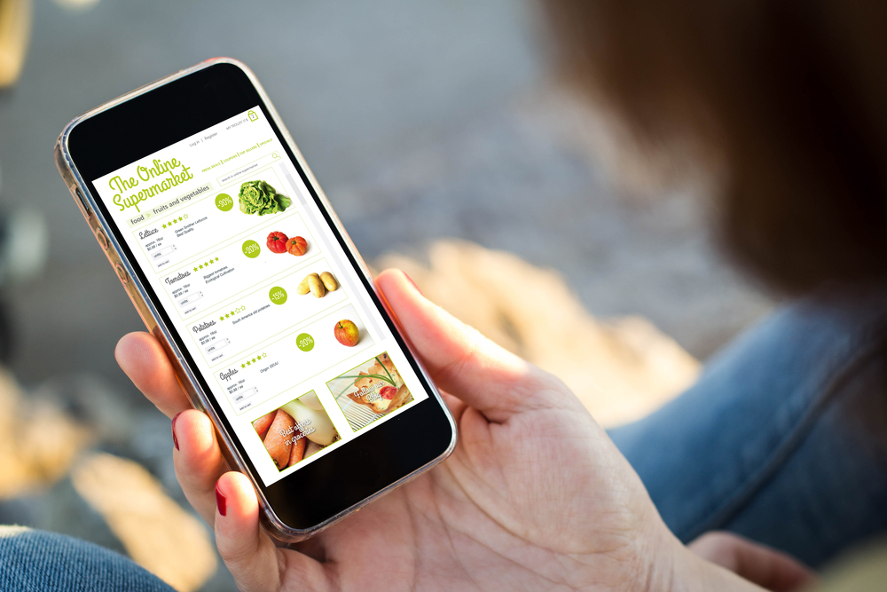 close-up view of young woman shopping groceries on online supermarket with her mobile phone. 