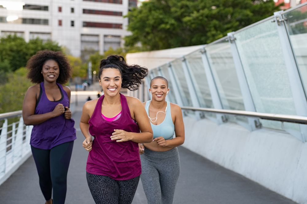 women jogging together on city bridge. Healthy girls friends running on the city street to lose weight. 