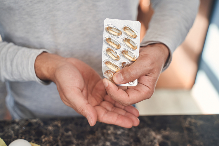 Man taking a gel capsule from a blister pack.