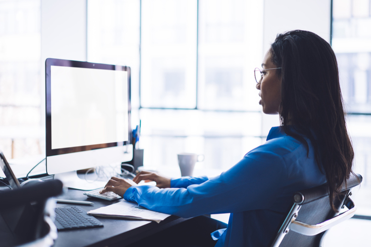 Lady sitting in front of empty screen of monitor.