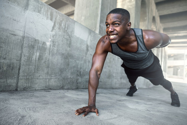 Intense push ups muscular male athlete training in city urban location, downtown city fitness lifestyle
