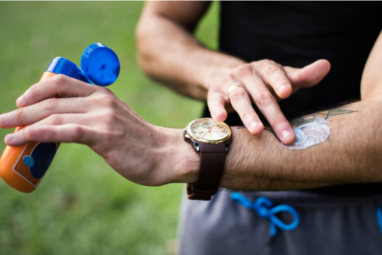 Man applying sunscreen on his arm.