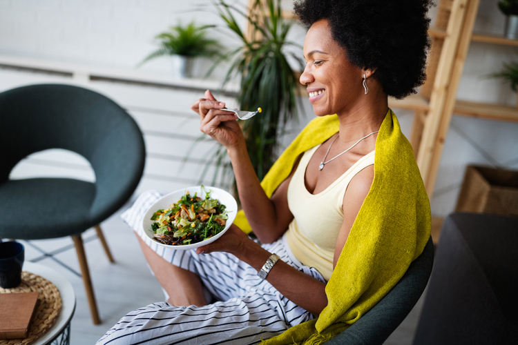 Woman eating vegetable salad at home.