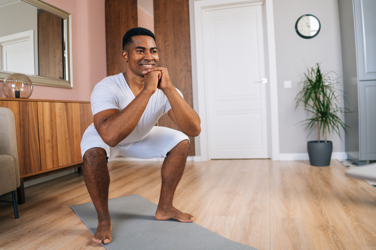 Man doing squats in a living room.