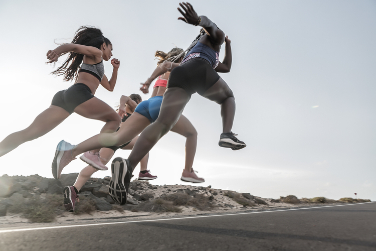 Low angle of powerful multiracial friends in sportswear running fast like wearing adidas futurecraft 4d.