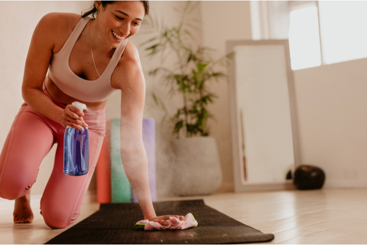 Woman cleaning and sanitizing yoga mat.