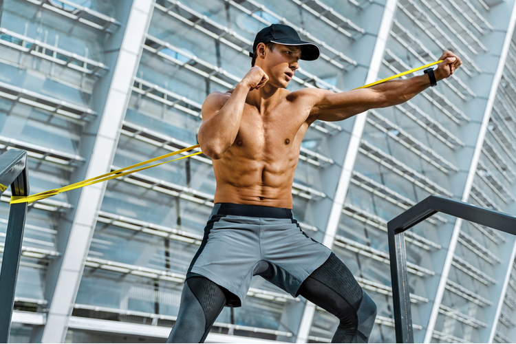 Strong looking man doing resistance band training in the morning.