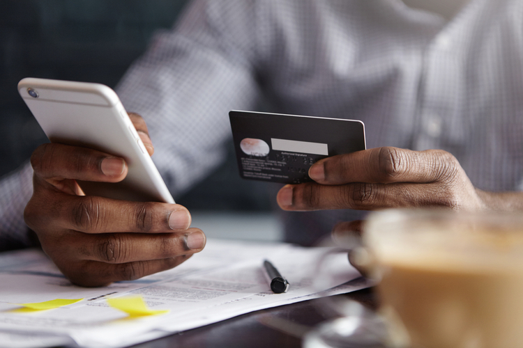 A man holding his debit card and his mobile phone while banking