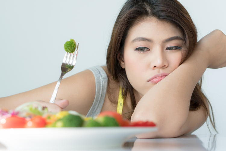 Woman looking at her food getting tired of different diet trends.