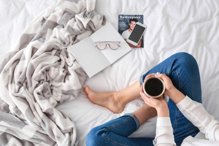 Young woman drinking coffee on sleepyhead usa copper topper bed in the morning.