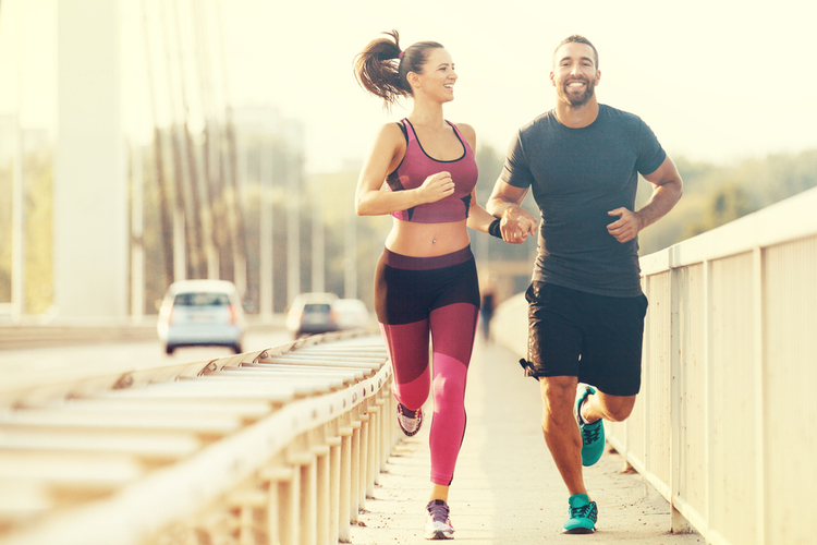 Early morning workout. Happy couple running across the bridge.