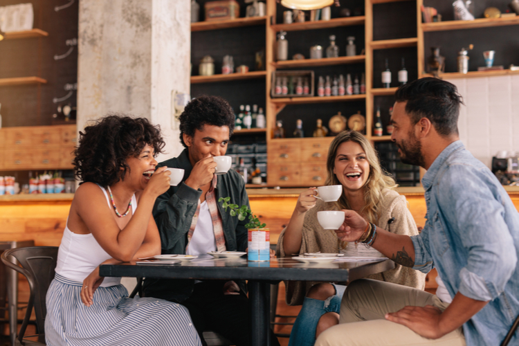 Diverse group of friends enjoying some coffee together in a restaurant and talking.