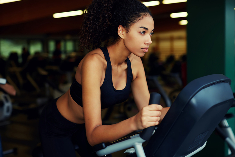 Focus woman ding cardio on a stationary bike.