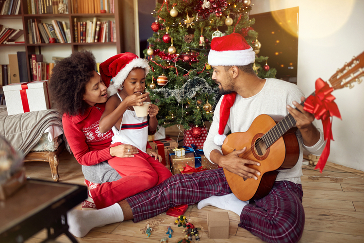 Happy Family Sitting On Floor Together and Listening Guitar Songs at Home on Christmas Holiday