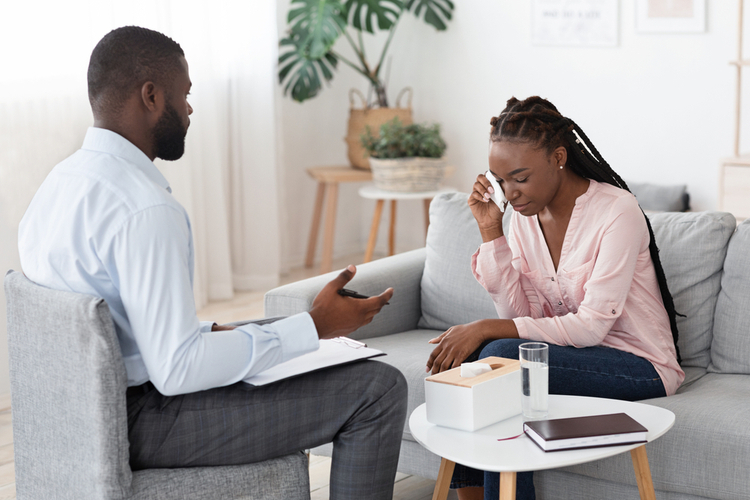 Black Male Psychologist Talking To Crying Woman During Therapy Session