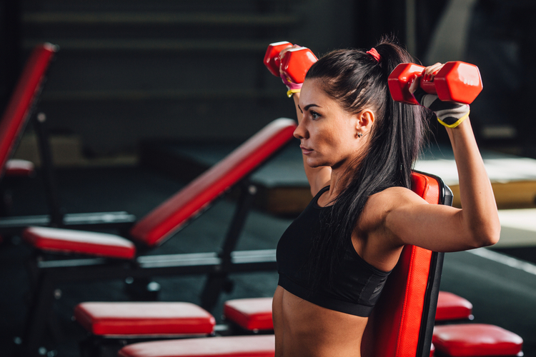 young sporty woman doing exercises with dumbbells in the gym