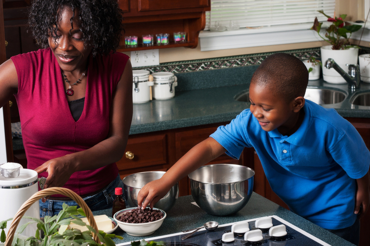 Boy reaches for chocolate chips while Mom is preparing to bake.