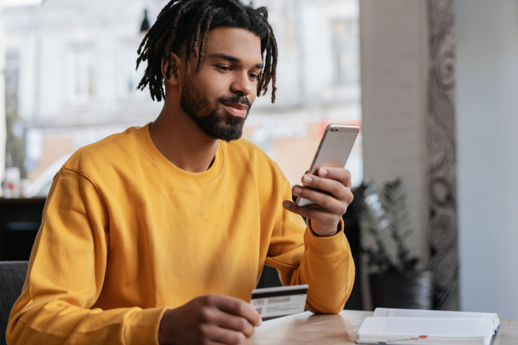 Man holding credit card and using his smartphone while mobile banking