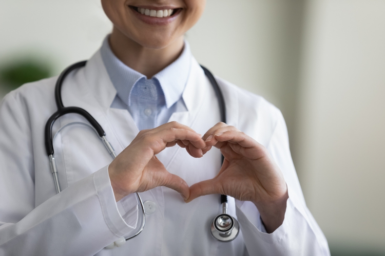 happy young Indian female GP doctor therapist physician making heart gesture 