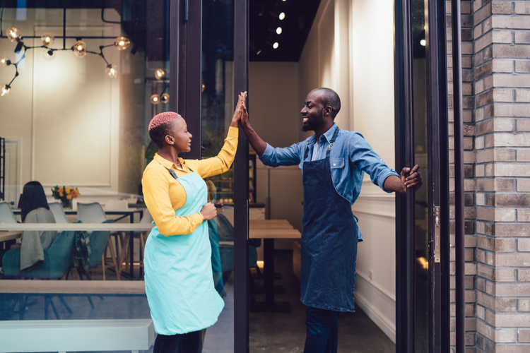 Joyful business partners in uniform looking at each other and giving high five