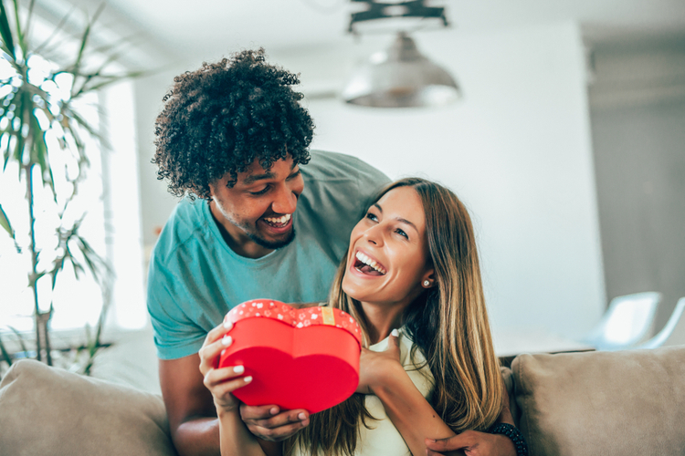 Man giving a surprise gift to woman at home