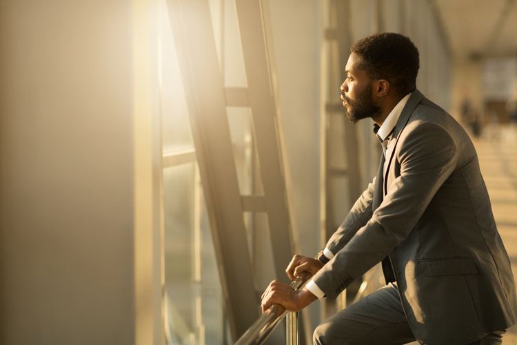 African-American Businessman Looking Through Window in Airport