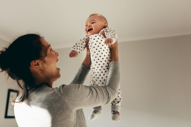 lifting her baby up and playing with him. 