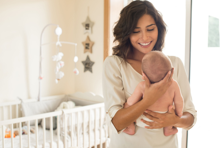 Young mother holding her baby in the bedroom